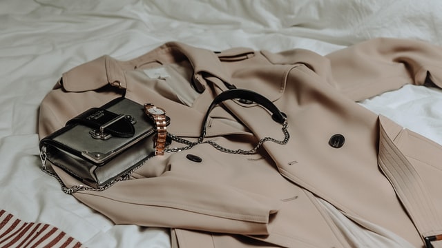 beżowy płaszcz, torebka i zegarek od projektanta, markowe ciuchy