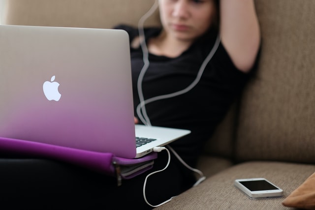 nastolatka używa Macbooka, słuchawki, telefon, prezent dla nastolatki