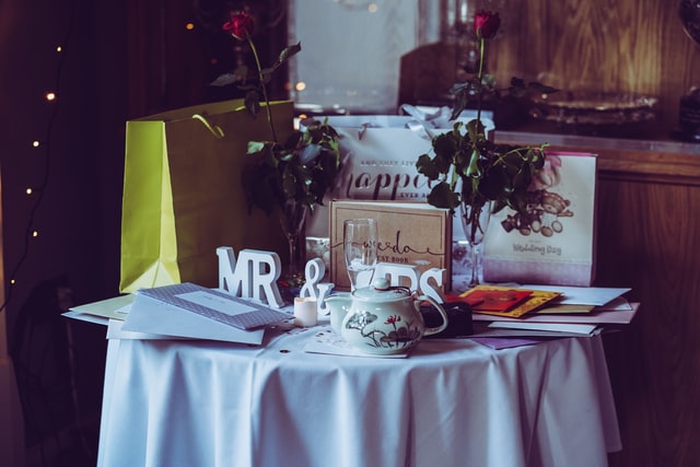 prezenty ślubne na stole, koperty, torby prezentowe