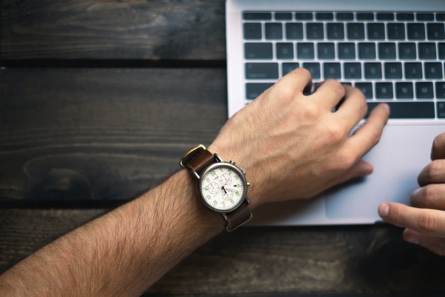 mężczyzna pisze na laptopie, MacBook, męski zegarek na skórzanej bransolecie