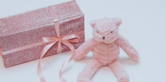 prezent dla dziewczynki w różowym, brokatowym papierze, z różową wstążką, różowy miś na dzień dziecka