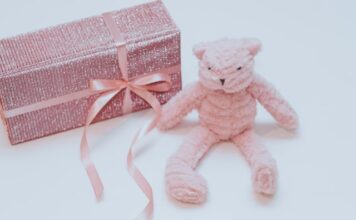 prezent dla dziewczynki w różowym, brokatowym papierze, z różową wstążką, różowy miś na dzień dziecka