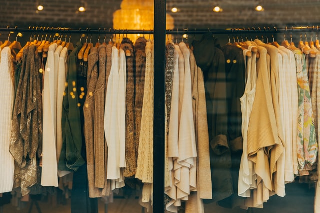 brązowe, beżowe i kremowe swetry na wieszaku w sklepie