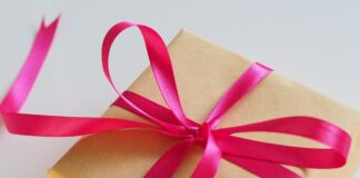 mały prezent w brązowym papierze owinięty różową wstążką