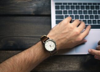 mężczyzna pisze na laptopie, MacBook, męski zegarek na skórzanej bransolecie